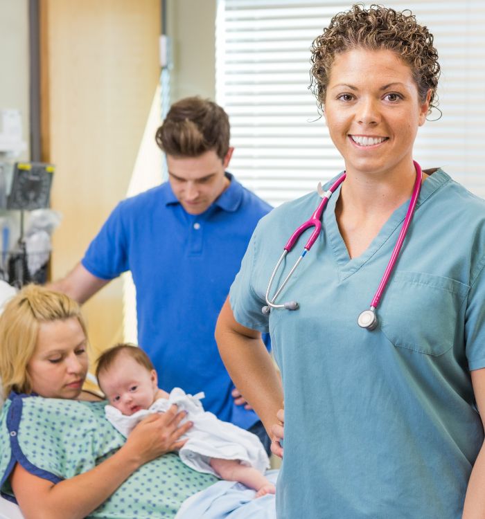 A woman in a blue shirt and a stethoscope standing next to a woman holding a baby.