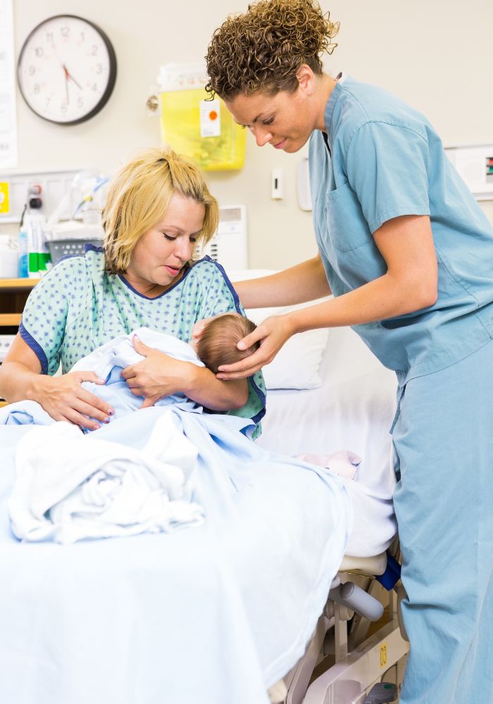 A woman holding a baby in a hospital bed.