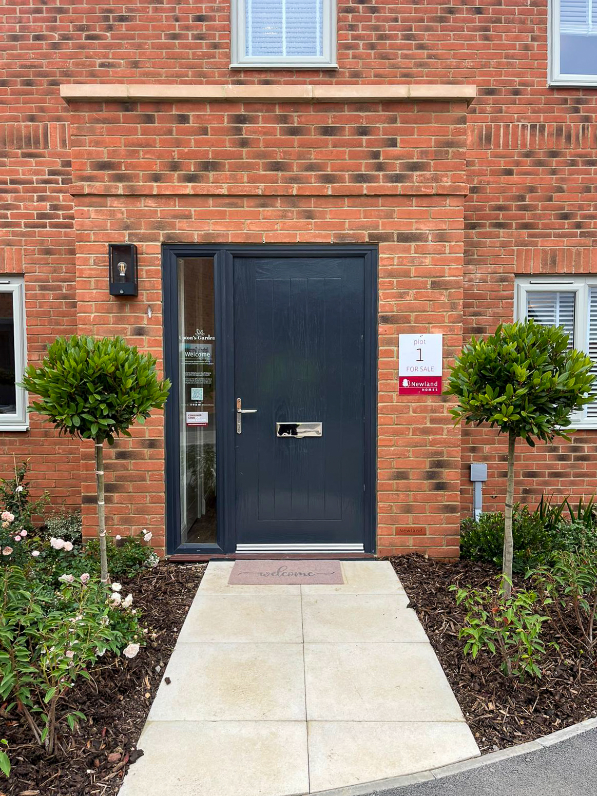 Front door at Upton's Garden in Whitminster framed by standard trees and planted borders, landscaped by Greenfields for Newland Homes