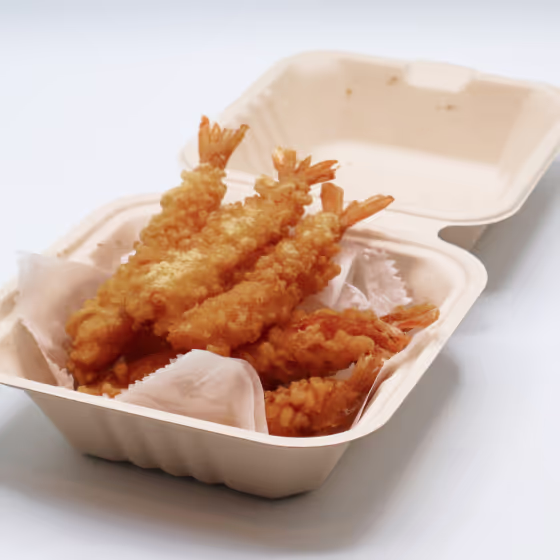 Takeout container holding golden brown fried shrimp tempura with tails intact.