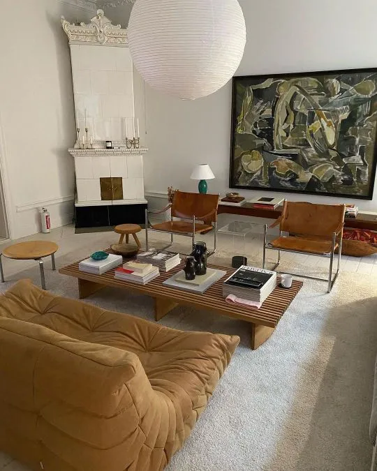 This may contain: a living room filled with furniture and a large painting on the wall above it's fireplace