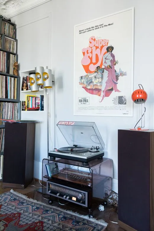 This may contain: a record player sitting on top of a table in front of a book shelf filled with books