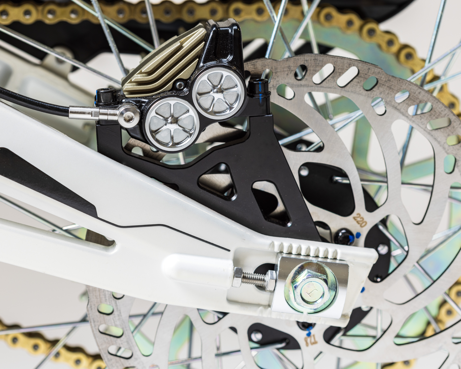 Close-up of a bicycle disc brake assembly with rotor, caliper, and white frame part.