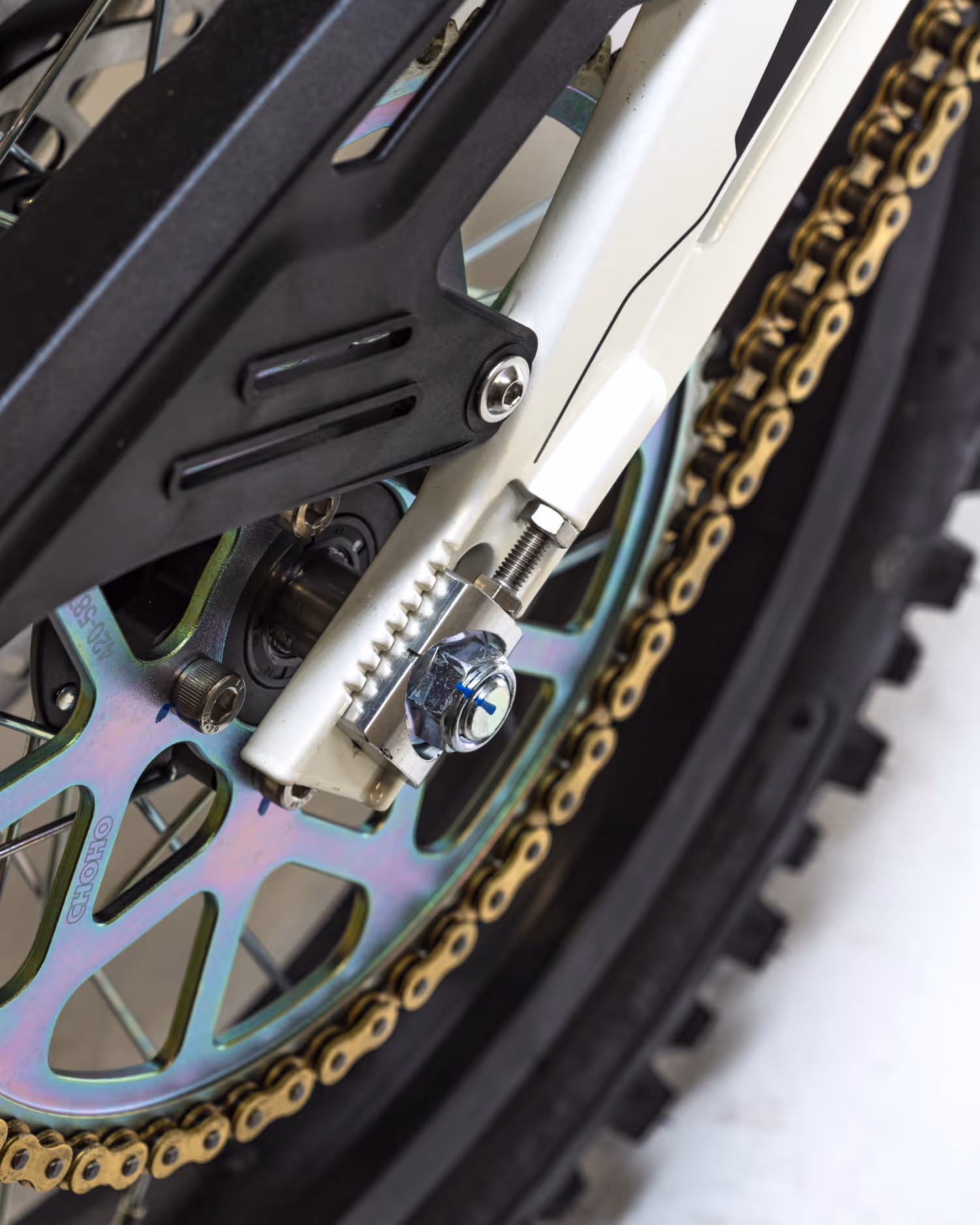 Close-up of a bicycle rear wheel showing the chain, sprocket, and part of the frame with a chain tensioner.
