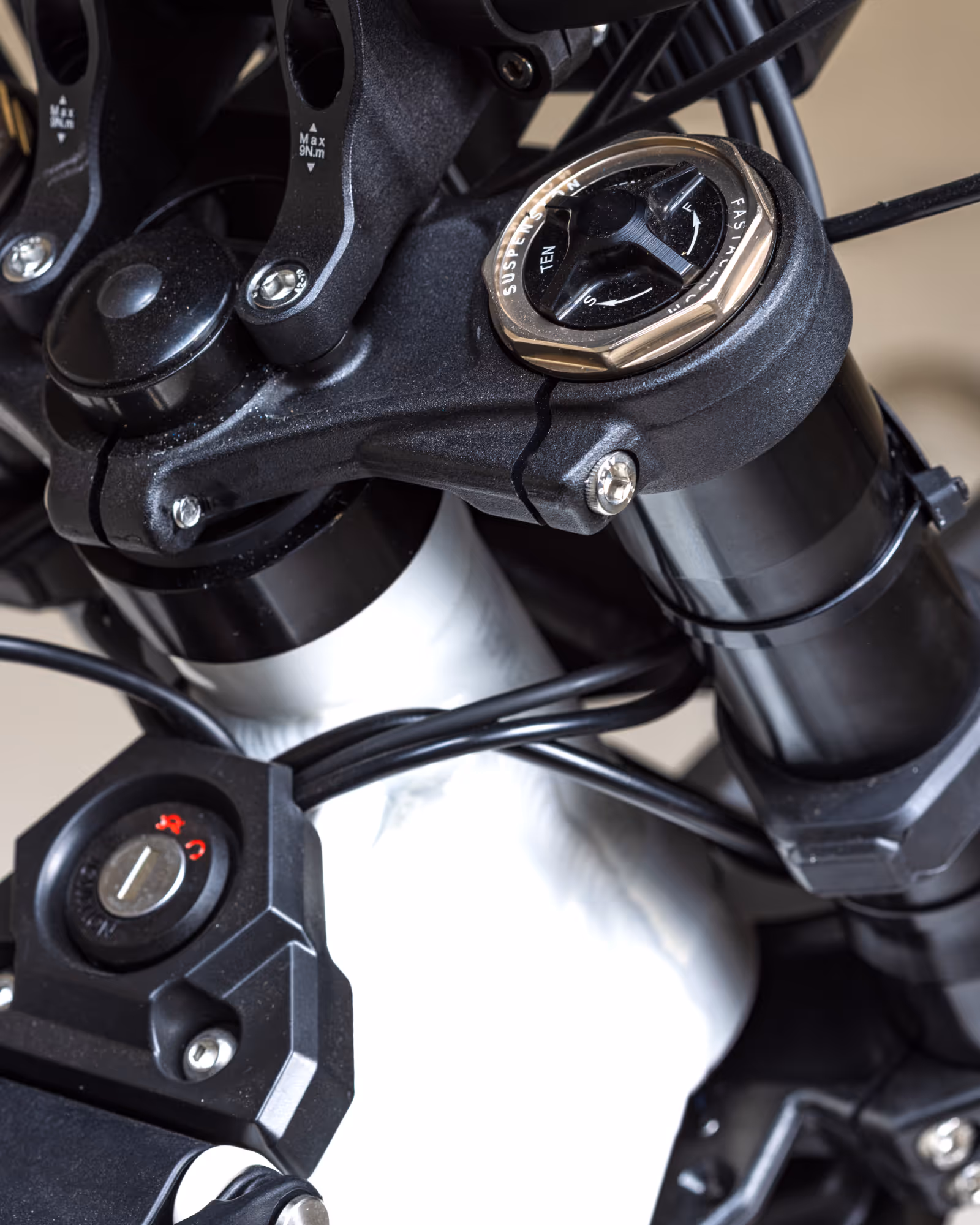 Close-up of a bicycle or motorcycle front suspension fork with adjustment knobs and cables.