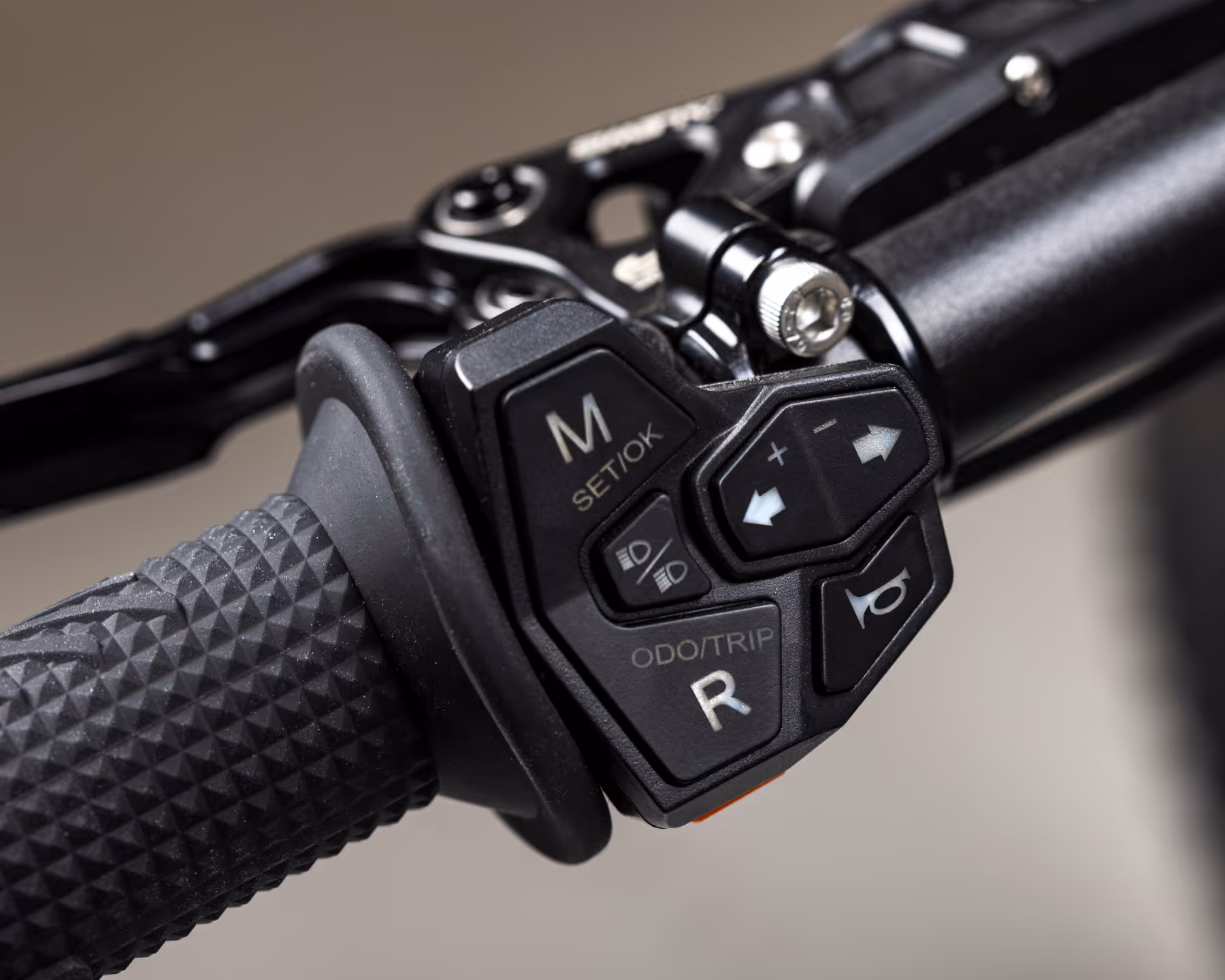 Close-up of a black motorcycle handlebar control with various buttons and switches.