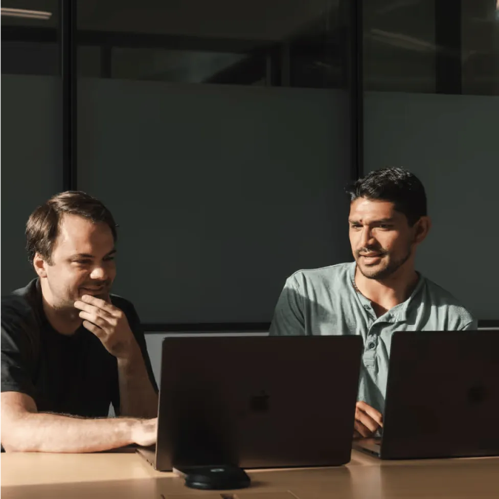 two adaptive employees conversing in front of their computers