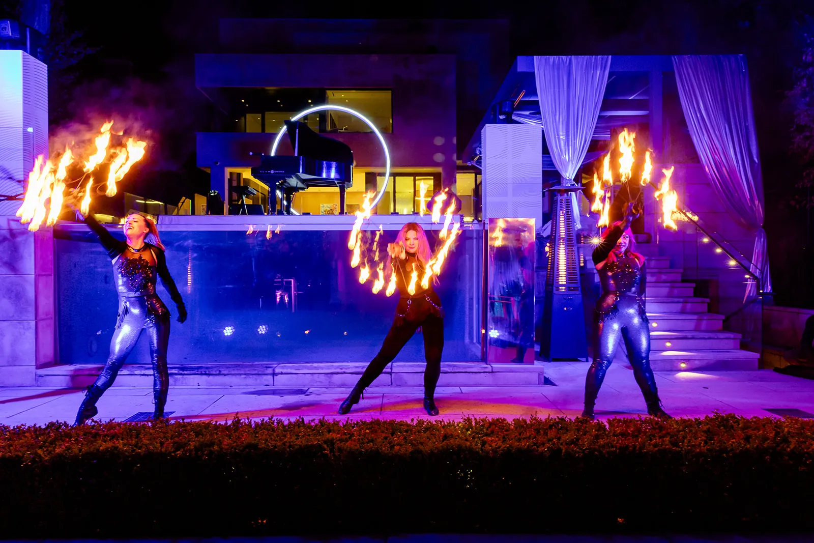 Fire performers spinning flames poolside at night