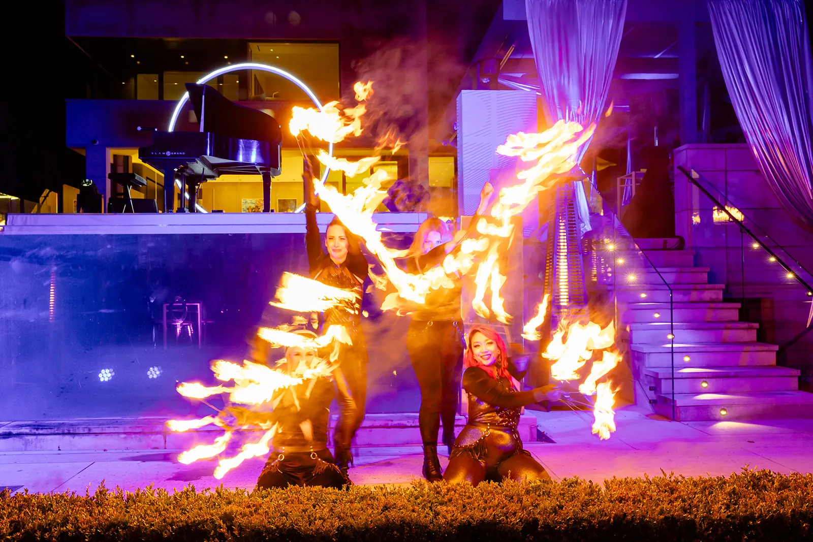Two fire performers with flaming fans beside a pool