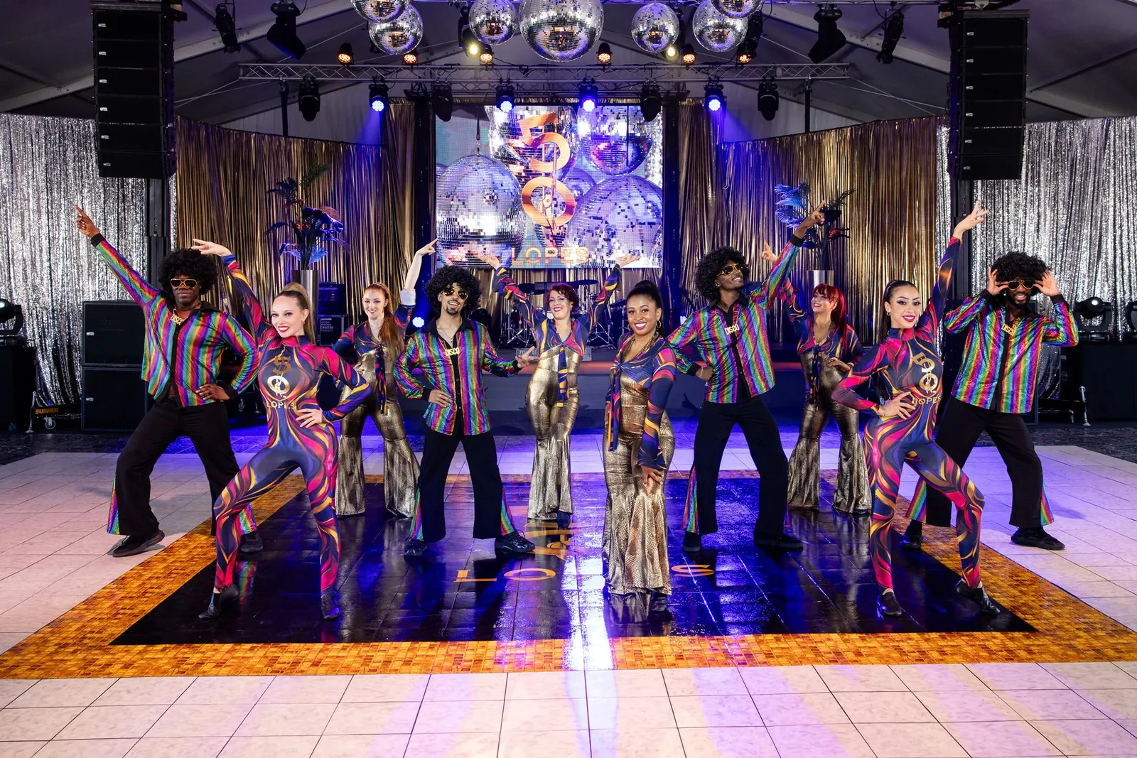 Studio 54 cast in disco costumes on a glowing dance floor
