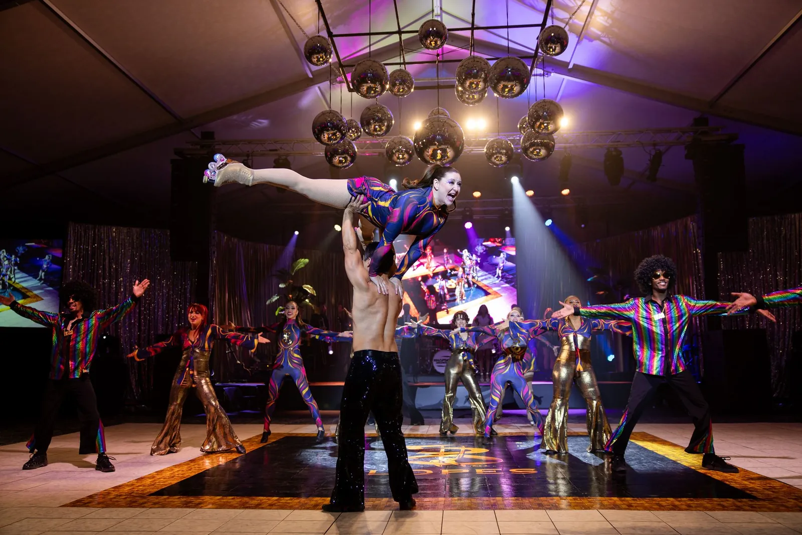 Acrobat lifted overhead by disco dancers