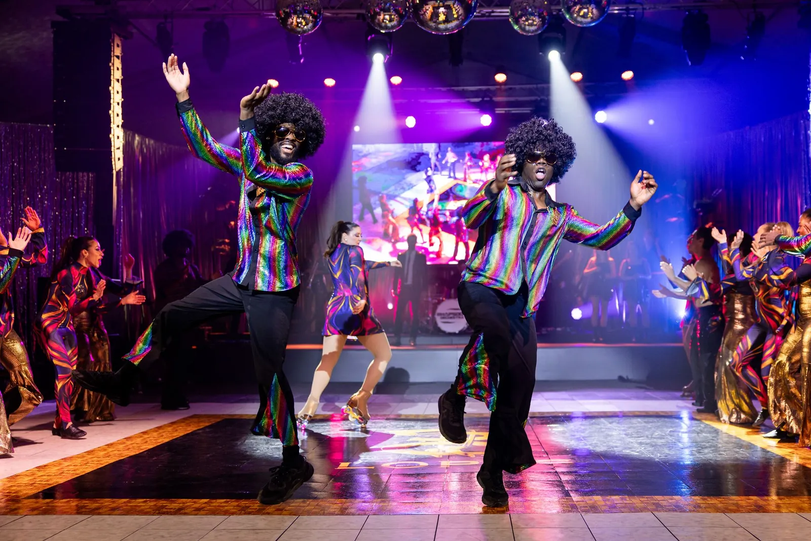 Disco dancers performing under purple stage lights