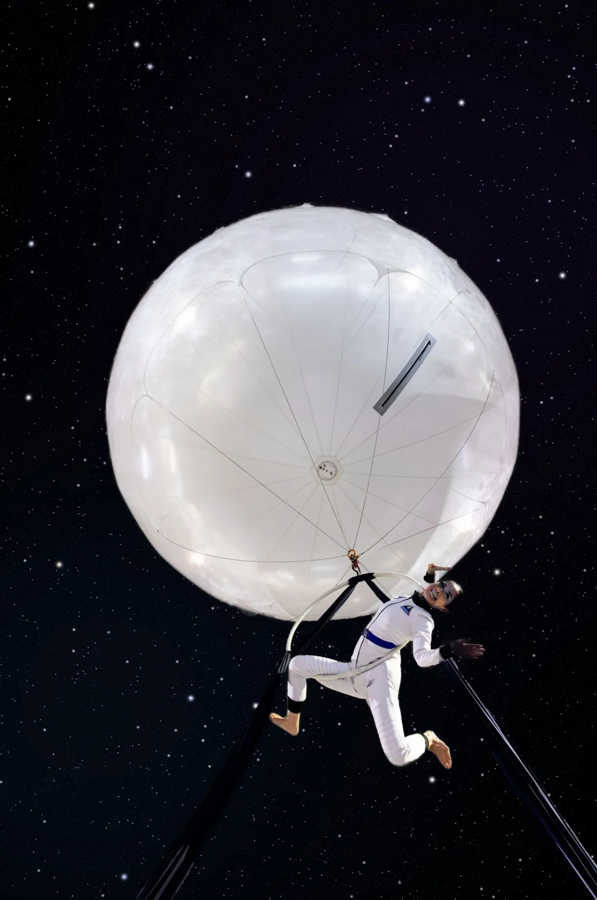 Aerialist performing beneath a glowing moon balloon