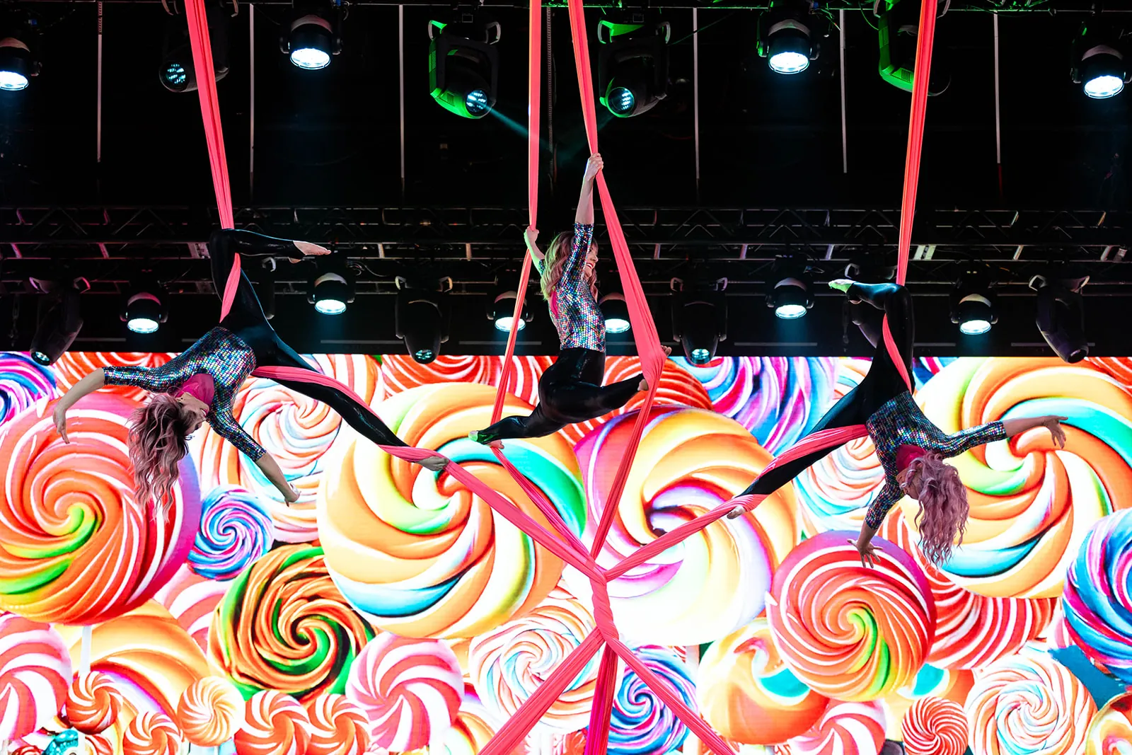 Aerialists dropping through red silks above the stage