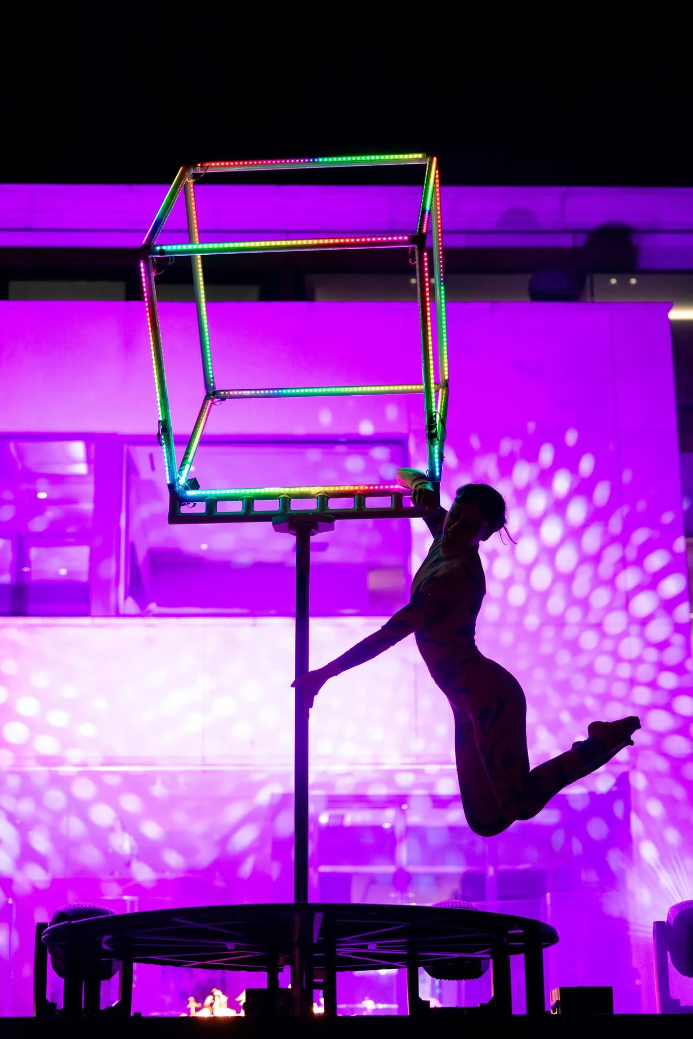 Aerialist posing beneath the glowing LED cube