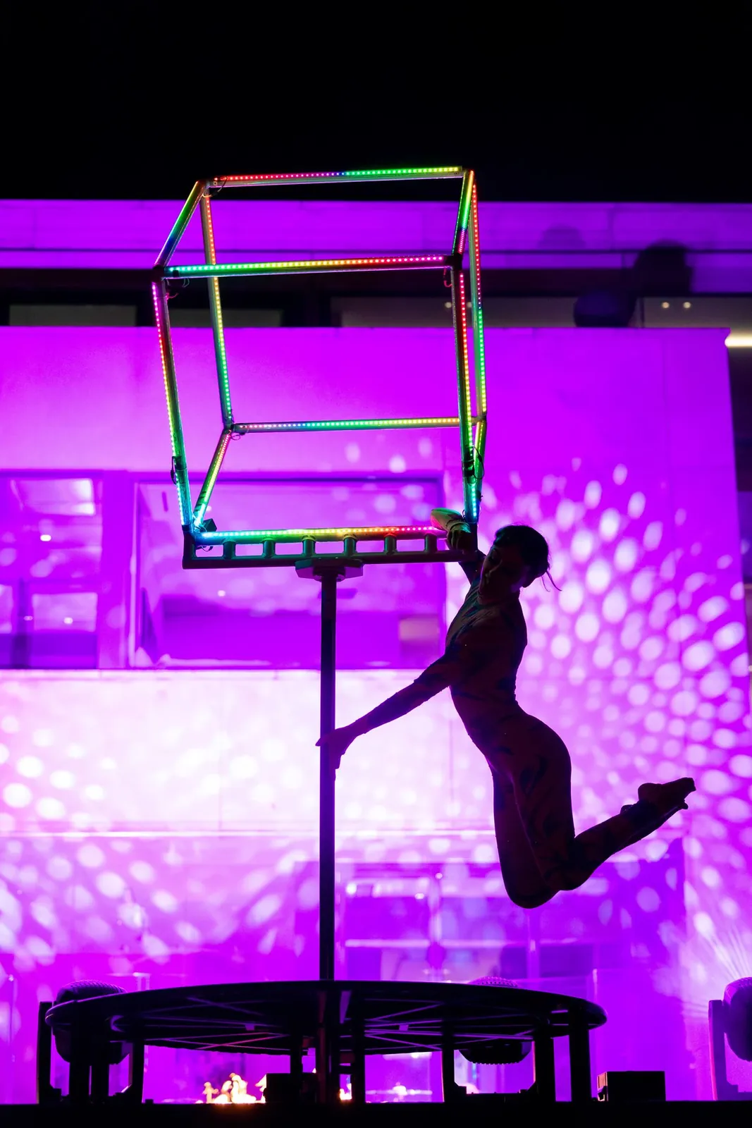 Aerialist striking a pose under the LED cube