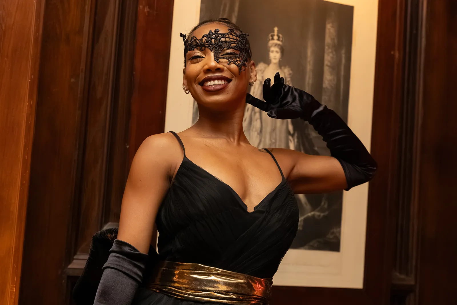 Masquerade performer in a lace mask and black gown posing