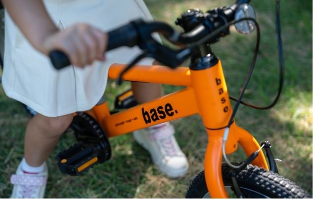 close up of a girl holding an orange bike base bikes epic sourcing