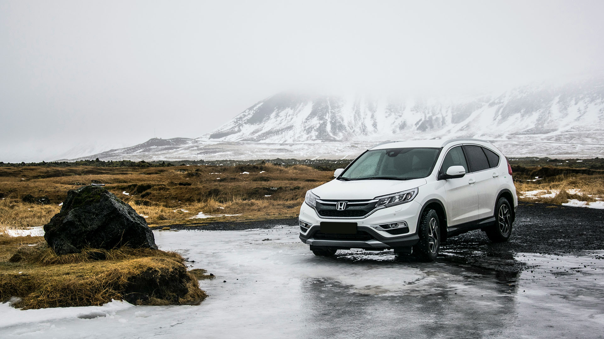 Honda CR-V driving through shallow creek in cold snowy terrain