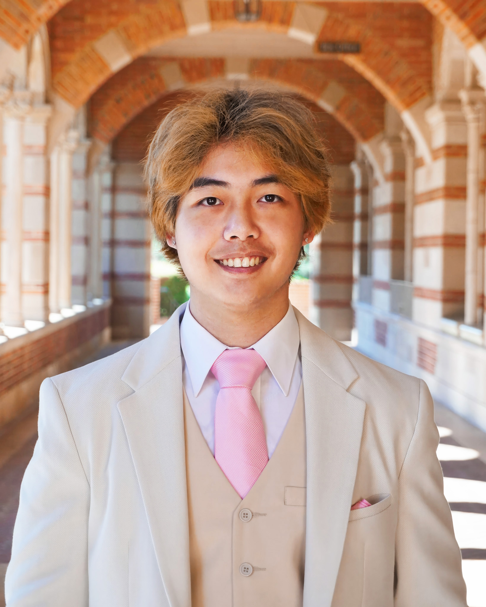 A man wearing a beige suit and pink tie