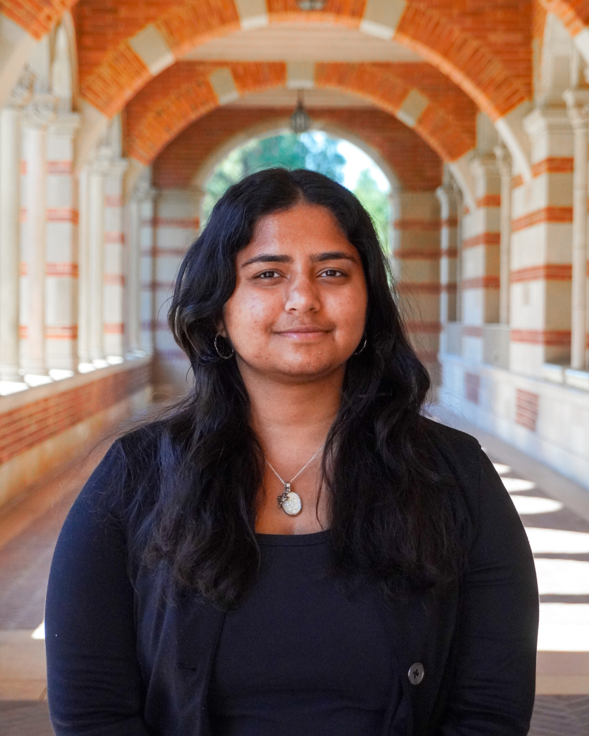 A woman wearing a black suit and necklace