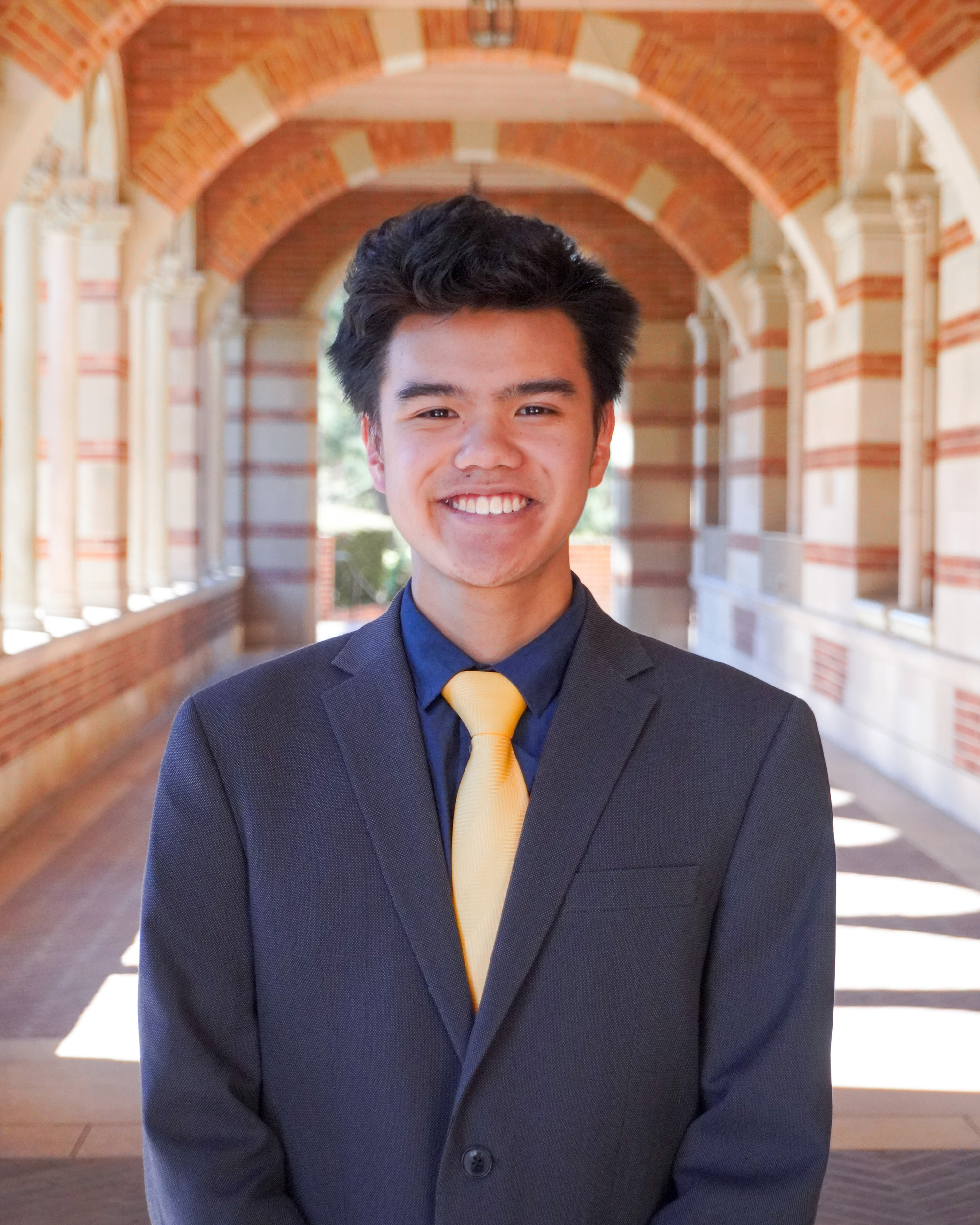 A man wearing a grey suit and gold tie