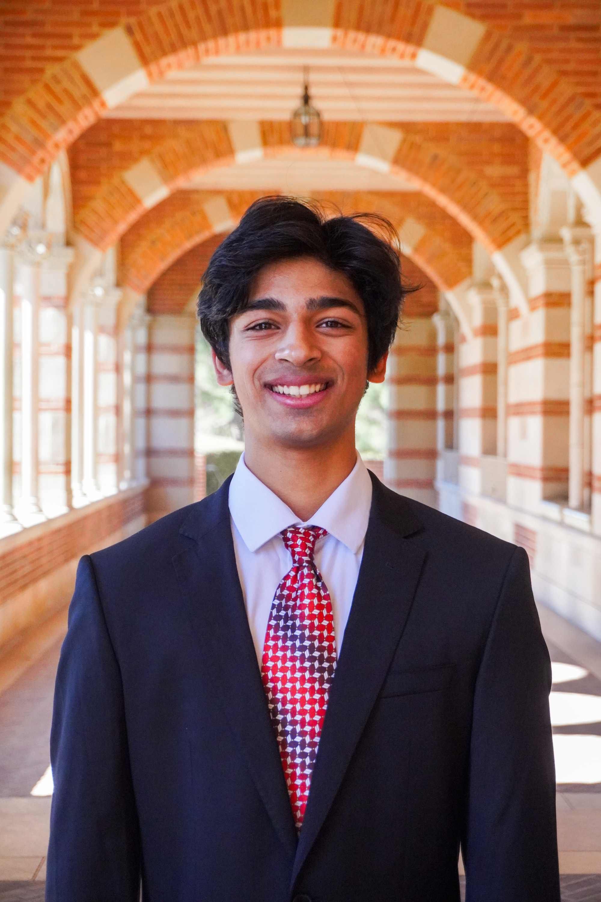 A man wearing a black suit and red tie