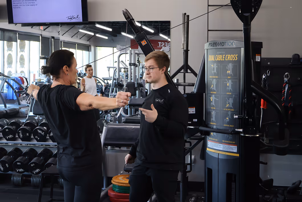 Trainer helping a client with back exercise machine at Todd Smith Fitness