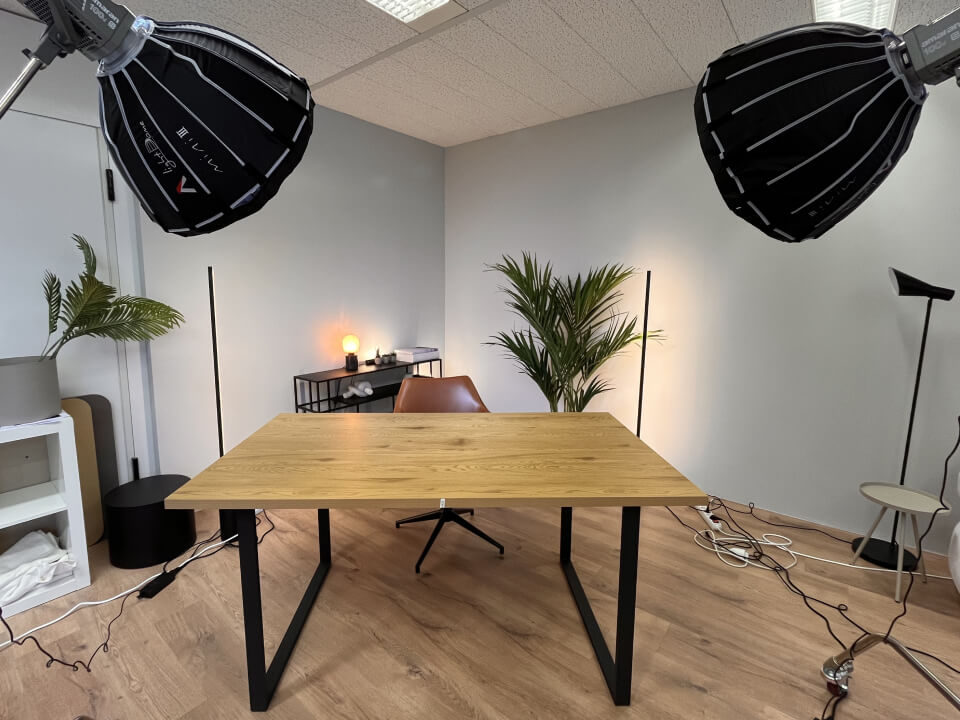Leerer Studioraum mit Schreibtisch, Pflanzen und Beleuchtungsequipment.
