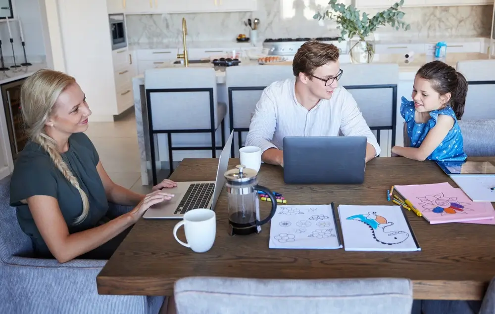 Parents working online with kid beside, showing balance of family and work.