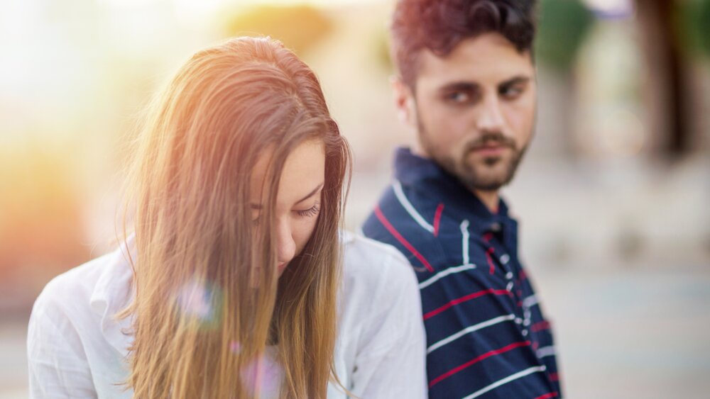 Woman sitting with her back to her partner, showing emotional distance in a rough patch.