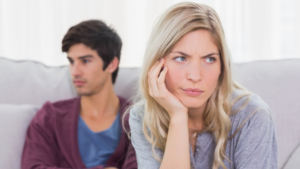 Unhappy couple sitting apart, not talking, showing poor communication.