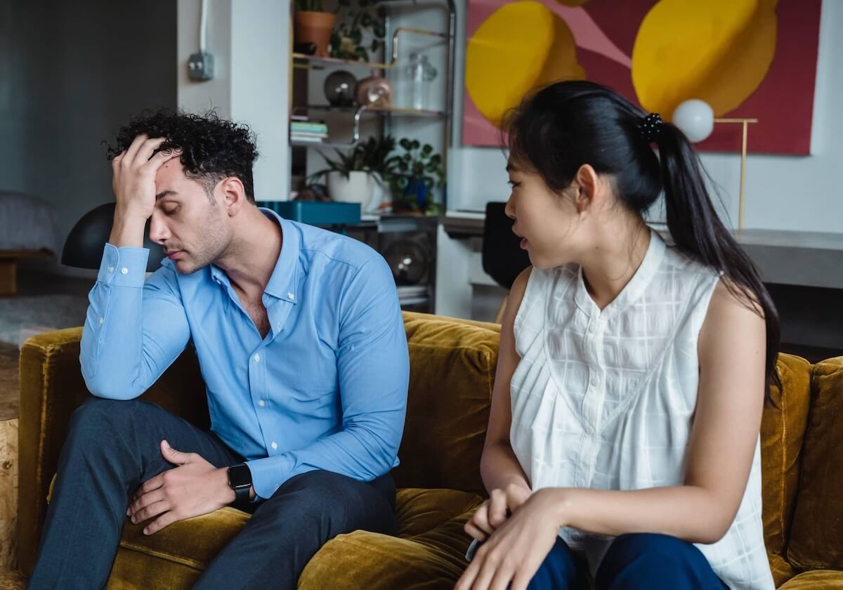 Couple sitting apart, looking away in silence, showing distance and tension.