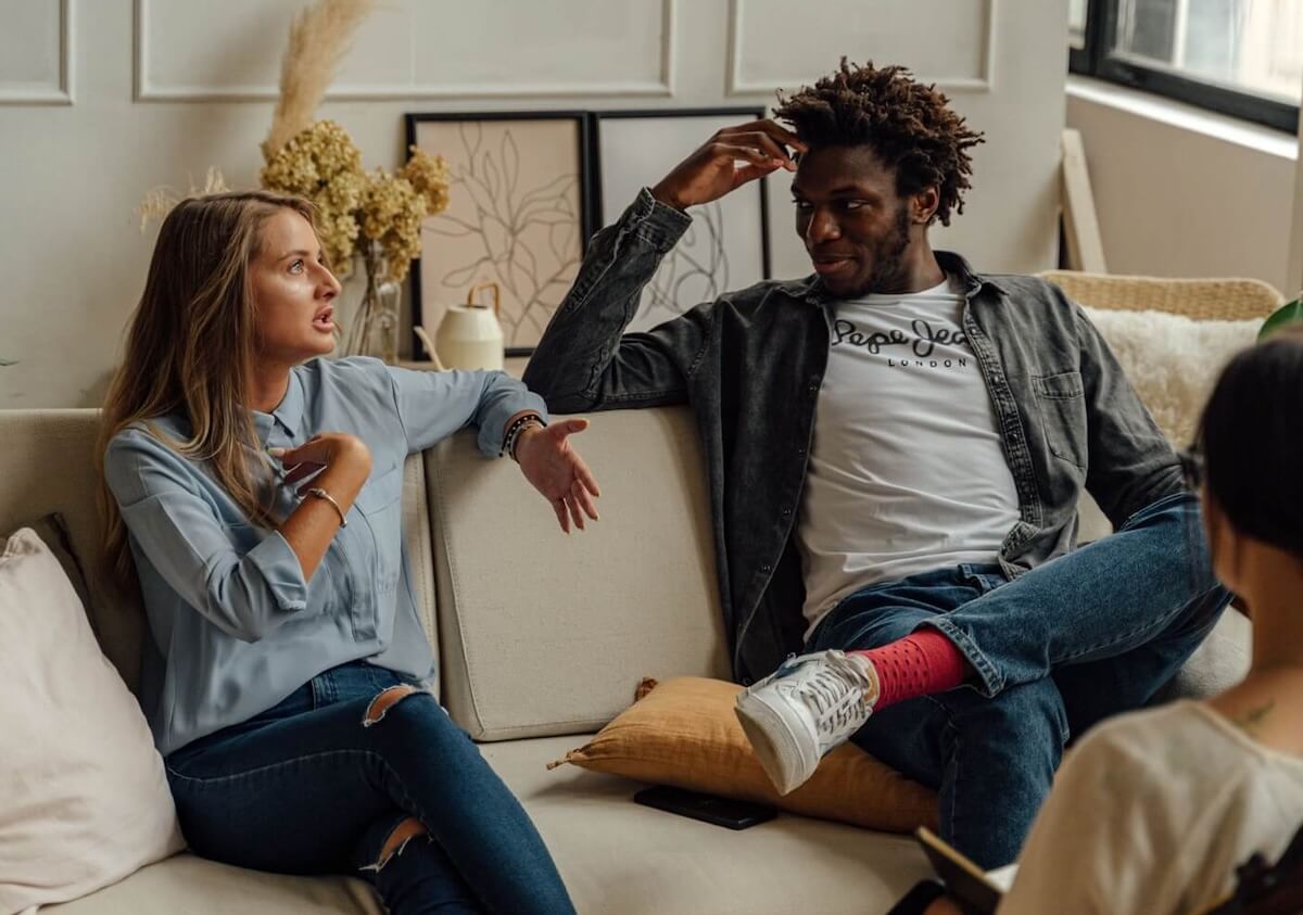Couple in a therapy setting where the woman is expressing her viewpoint while the man listens attentively, symbolizing open communication and growth in counseling.