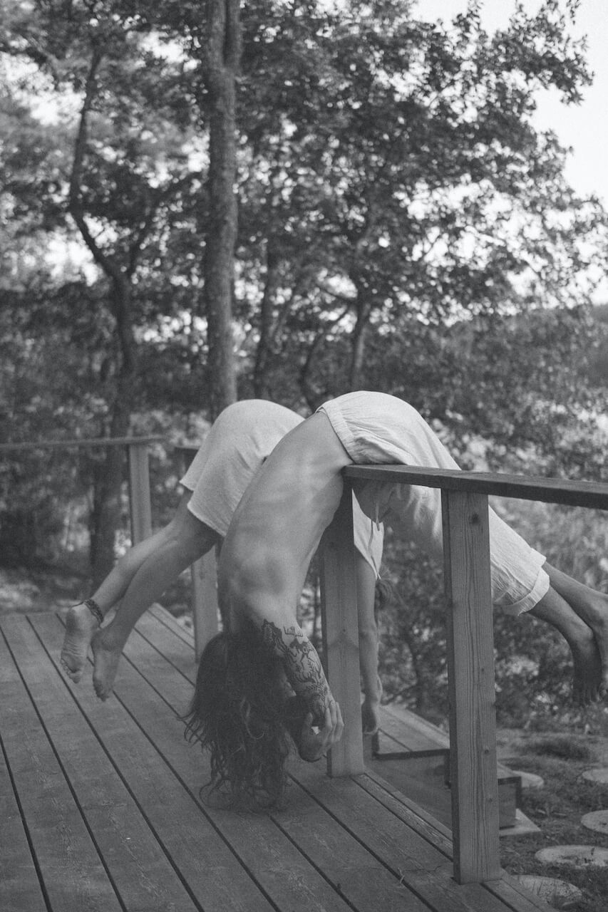 Two individuals balancing carefully on a wooden fence, symbolizing the delicate balance of setting and maintaining realistic relationship goals for the new year.