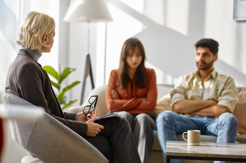 A married couple sitting together in a therapist’s office, attentively listening during a psychological consultation, symbolizing preparation and openness for their first couples guidance session.