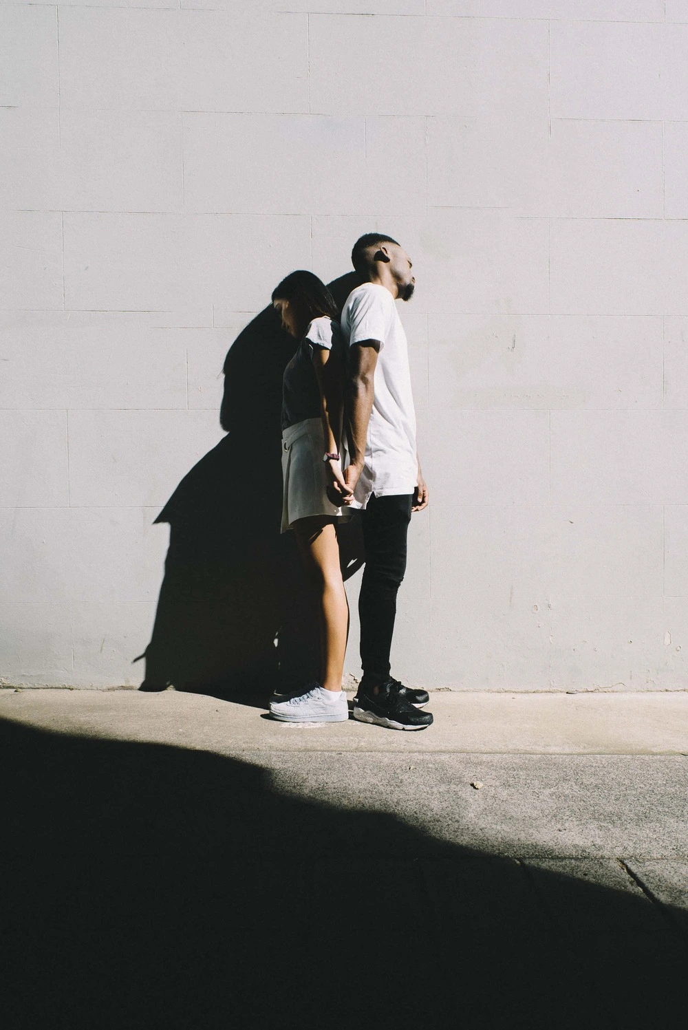 Couple standing back-to-back in the sun, symbolizing relationship tension, conflict, and the potential for reconnection through effective communication.
