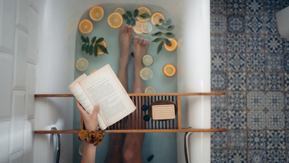 Person relaxing in a warm aromatherapy bath with a book, symbolizing self-care, healthy boundaries, and saying yes to personal needs.