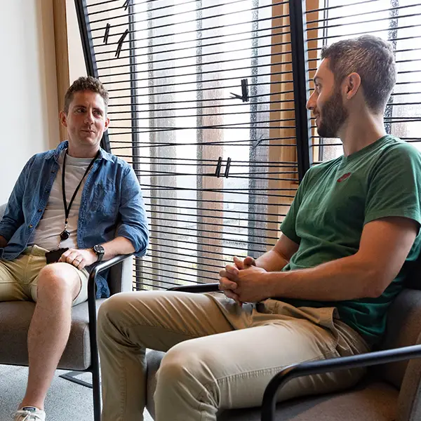 Two men in discussion sitting by a window