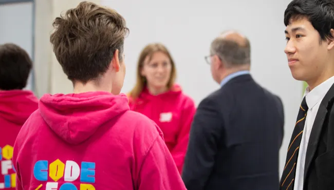 Students in discussion, one wearing a Code4Life hoodie