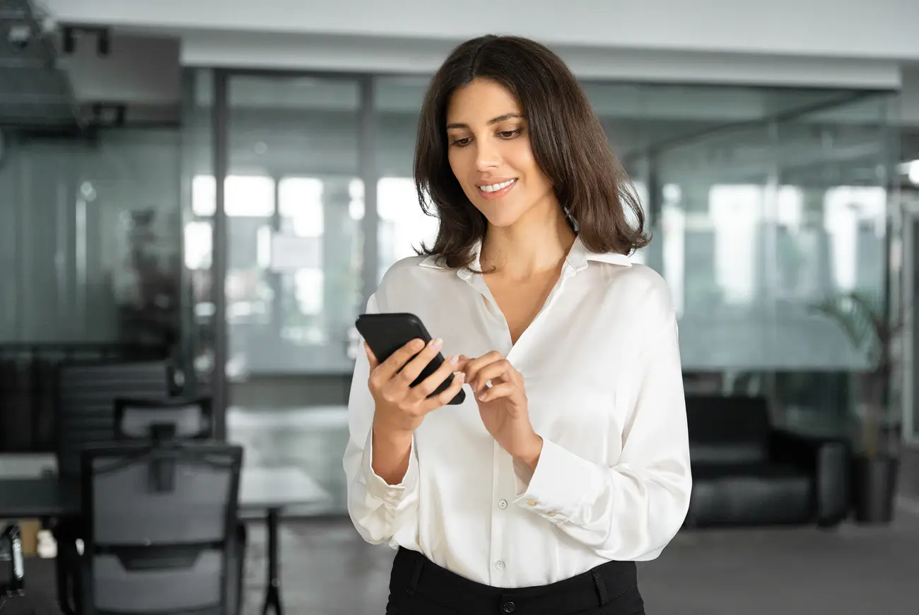 A businesswoman using her smartphone in a modern office. 