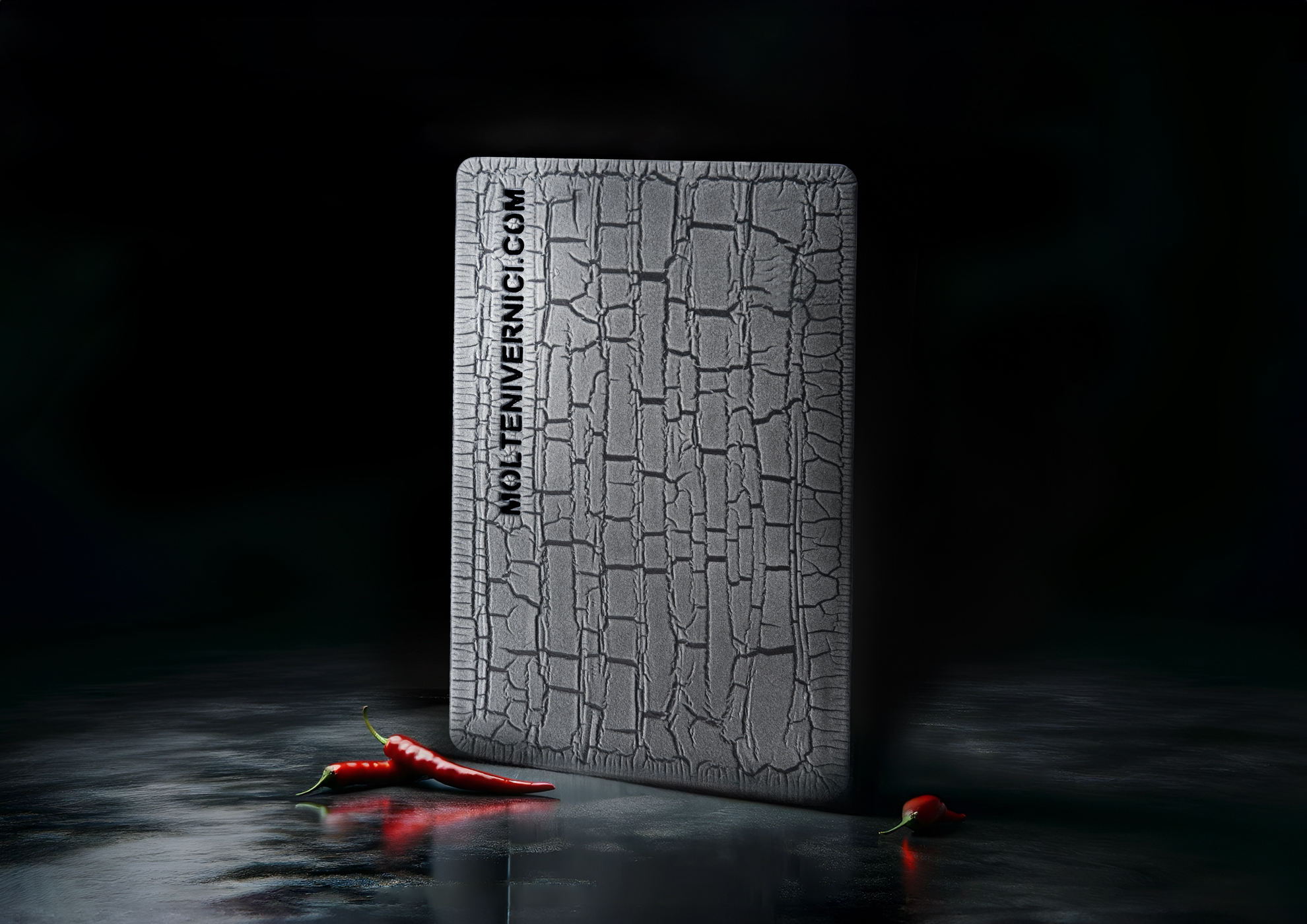Plaque texturée grise avec des piments rouges sur surface réfléchissante sombre
