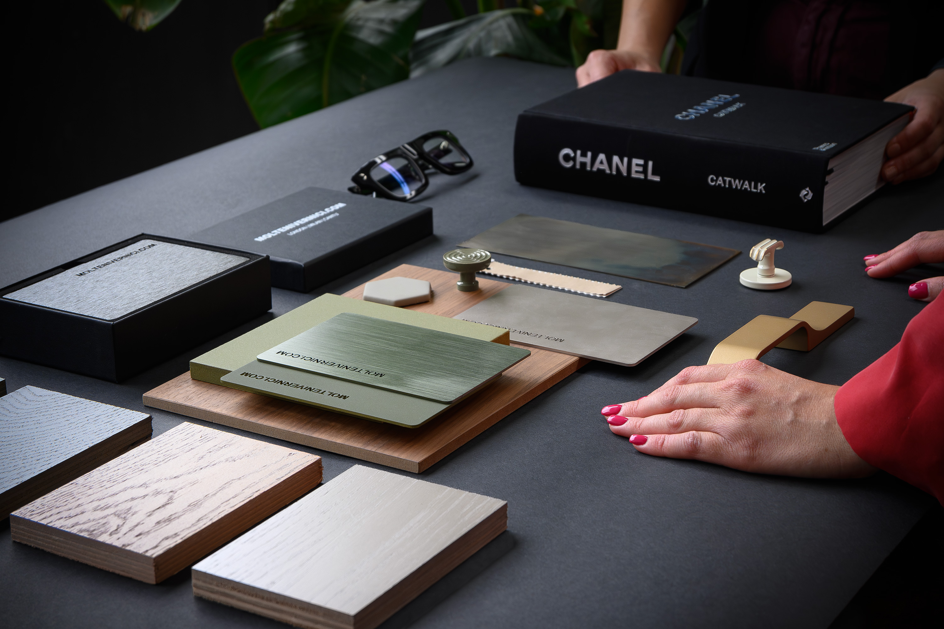 Campioni di materiali e libro Chanel su tavolo nero con mani