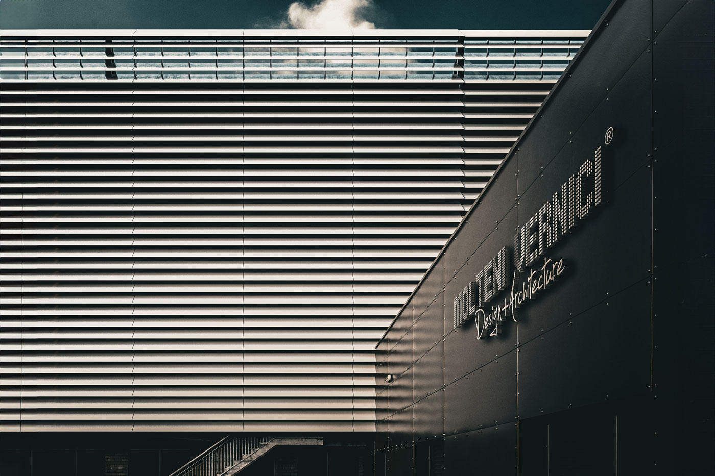 Bâtiment moderne avec façade en métal rayé et nuage dans le ciel