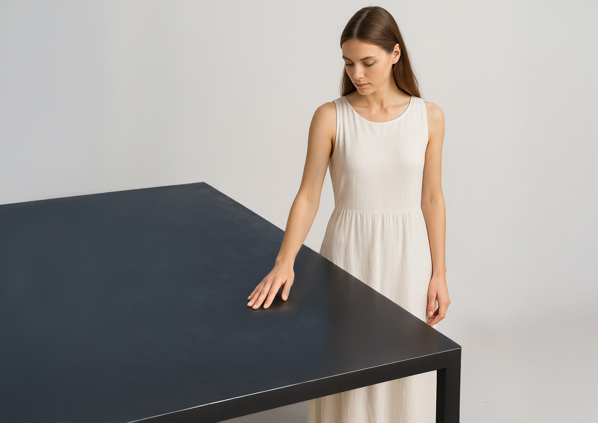 Une femme en robe blanche touchant une table noire minimaliste