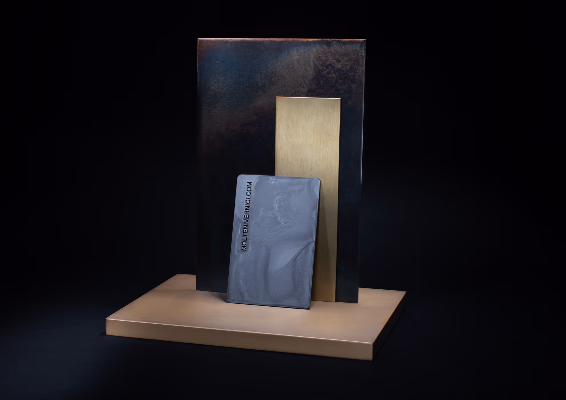 Muestras de acabados MOLTENI-VERNICI en tonos metálicos sobre fondo oscuro