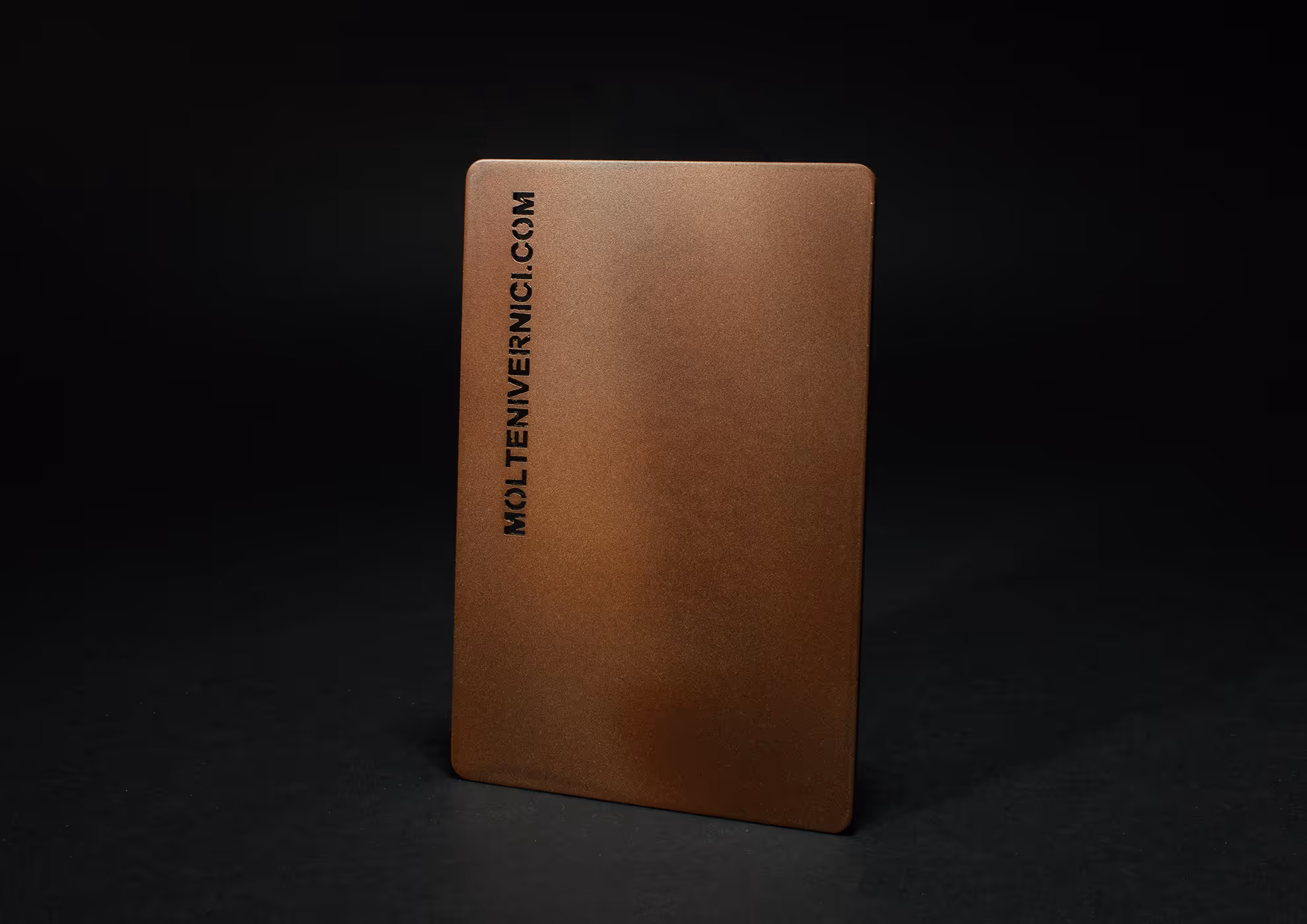 Tarjeta metálica de MOLTENI-VERNICI con acabados en tono bronce oscuro
