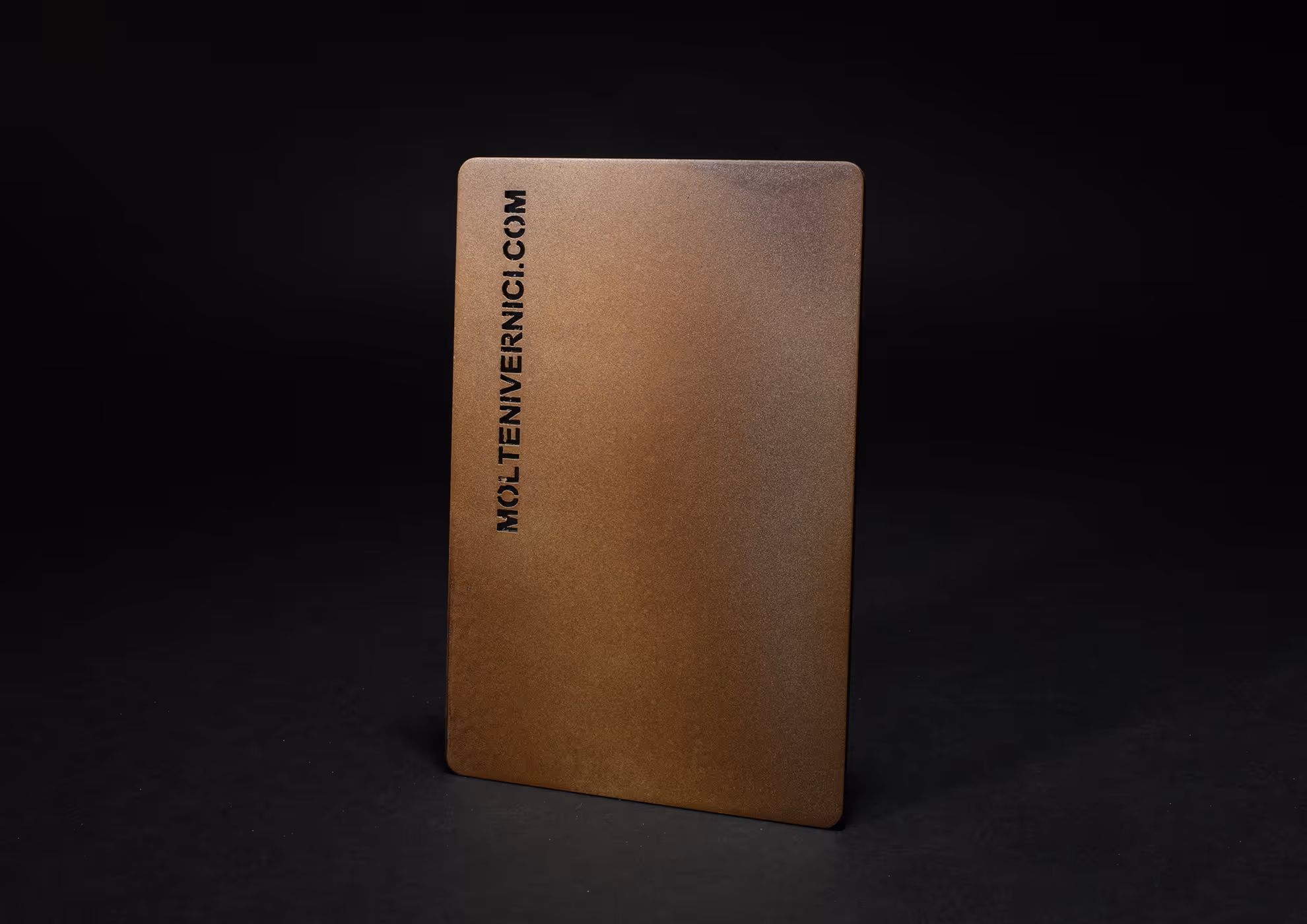 Tarjeta metálica de MOLTENI-VERNICI con acabados en tono dorado mate