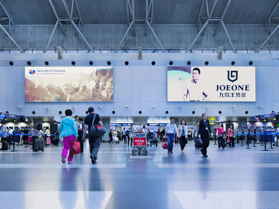 Airport terminal with digital billboards, travelers walking, Joeone advertisement visible