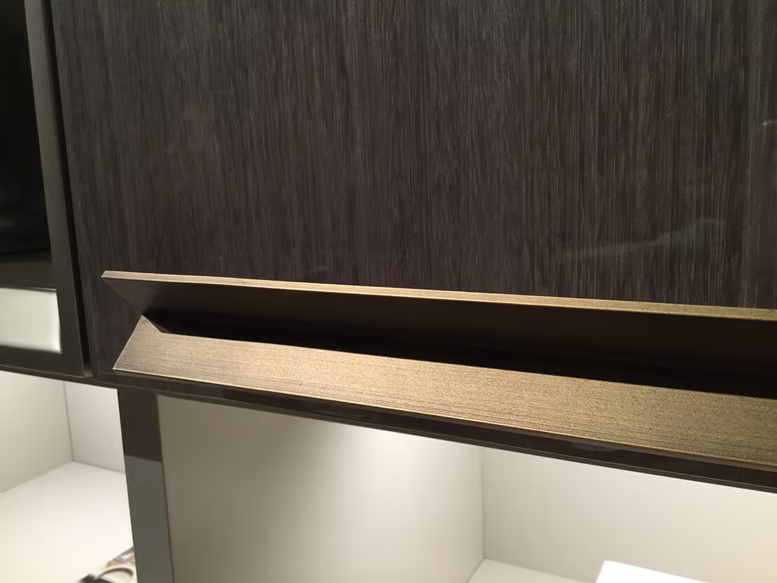 Finition premium MOLTENI-VERNICI : poignée dorée sur meuble noir élégant